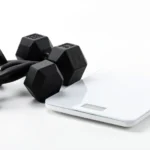 Muscular silhouette standing beside a bathroom scale, with a small dumbbell, representing why BMI can misread athletic bodies; no text in image, no real person's face