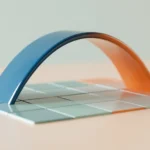 A smooth curved ribbon of colored material rising over a flat grid-like tile surface on a light desk