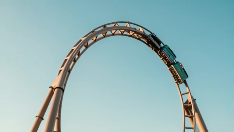 Roller coaster cars at the top of a steel loop against a blue sky
