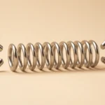 A metal coil spring with a hook at each end on a plain light background