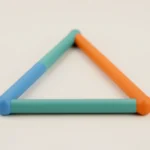 A closed triangle made of three colored rods joined at the corners, lying on a light desk