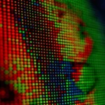 An extreme close-up of a screen showing individual red, green, and blue pixels forming part of an image