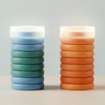 Two tall stacks of colored tokens side by side on a light desk with a soft translucent band around their tops, suggesting uncertainty