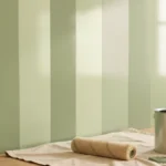 Five painted sample boards in the same color arranged from flat to high gloss, catching window light at different strengths, no people present