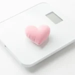 A gentle balance scale with a small heart resting on it, a soft calm illustration of the pregnancy weight concept, no text in the image and no real person