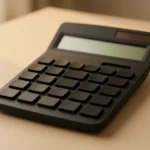 A simple handheld calculator resting on a plain desk showing a small M memory indicator on its display, no other text, no hands, no face